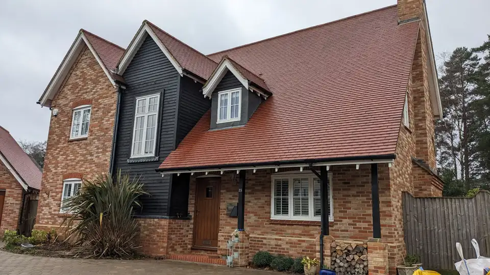 A red brick house with a freshly cleaned roof and block paved drive