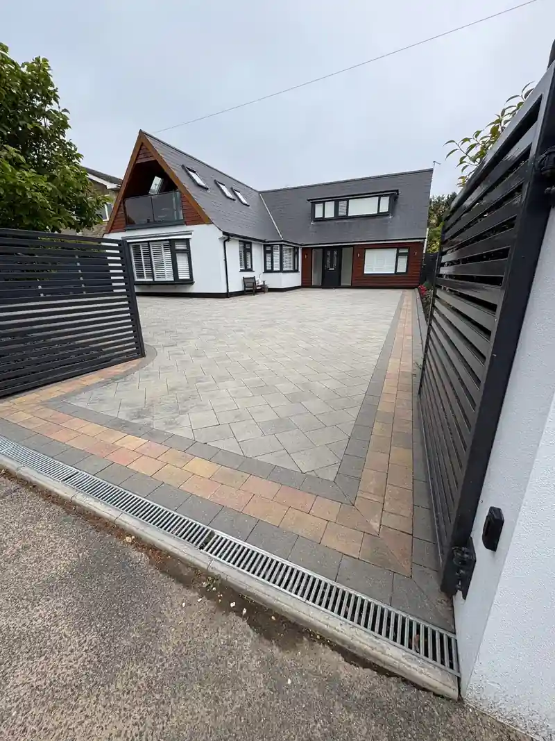 A modern house with a grey block paved drive and gates