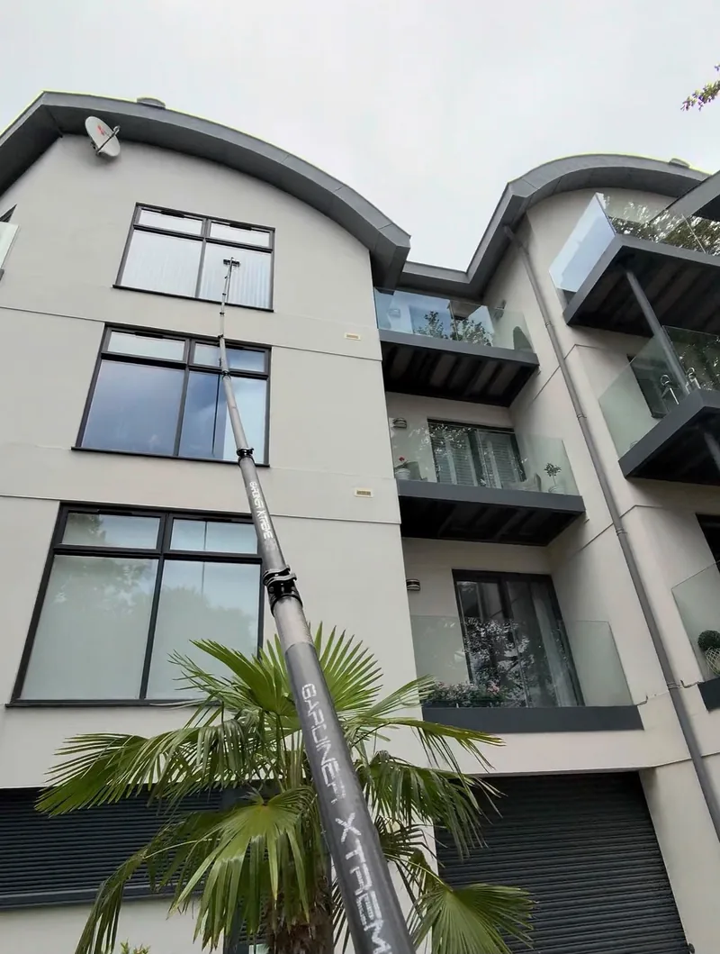 Cleaning the windows of a block of flats with a water-fed pole